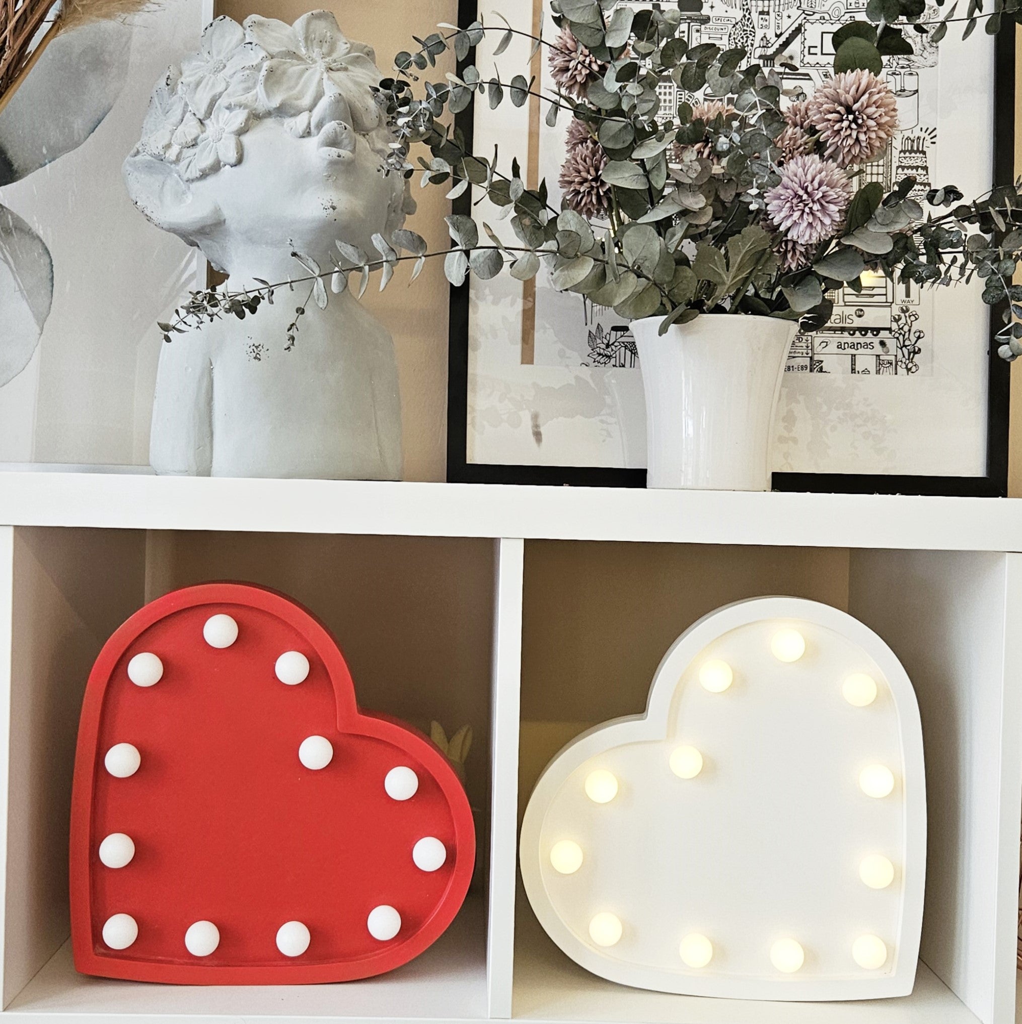 Photograph featuring two PIKU Heart Light Lamps in red and white, elegantly displayed on a surface.
